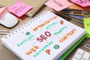 Notizbuch mit handgeschriebenen SEO-Begriffen wie Ranking, Keywords und Optimization, umgeben von bunten Notizzetteln