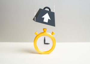 Gelbe Stoppuhr, über der ein schweres Gewicht mit Pfeil schwebt, Symbolbild für große Dateien und langsame Ladezeit