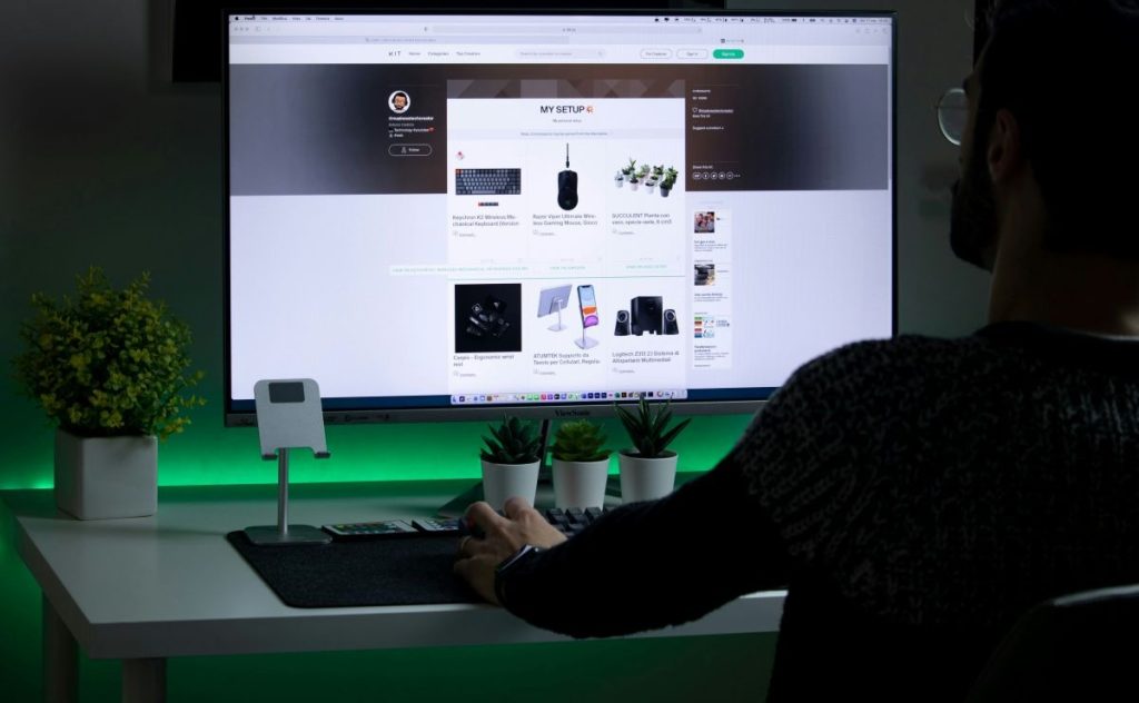 Mann sitzt vor einem Computer Bildschirm und macht Webdesign.