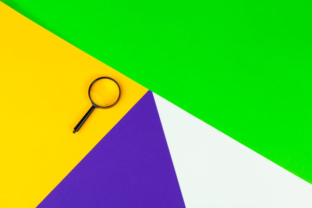 Lupe auf buntem, geometrischem Hintergrund.