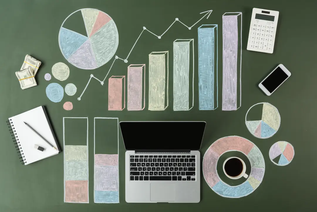 Laptop mit handgezeichneten Diagrammen und Statistiken auf einem Tisch.