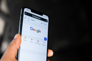 Hand hält iPhone mit geöffneter Google-Startseite