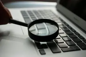 Lupe liegt auf der Tastatur eines silbernen Laptops