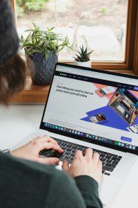 E-Commerce-Website auf Laptop-Bildschirm mit Shopify-Startseite und arbeitender Person