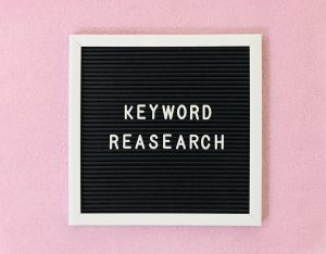Buchstabentafel mit der Aufschrift Keyword Research an rosa Wand