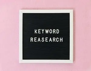 Buchstabentafel mit der Aufschrift Keyword Research an rosa Wand