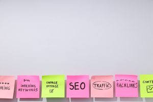 Bunte Haftnotizen an weißer Wand mit handgeschriebenen SEO-Begriffen wie Keywords, Backlinks, Traffic und Onpage/Offpage