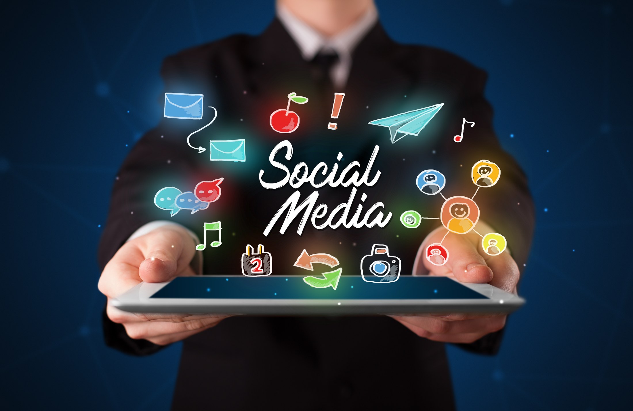 Geschäftsmann hält Tablet mit Social-Media-Icons – Content-Betreuung und Social Media durch Ihre Branding Agentur Passau