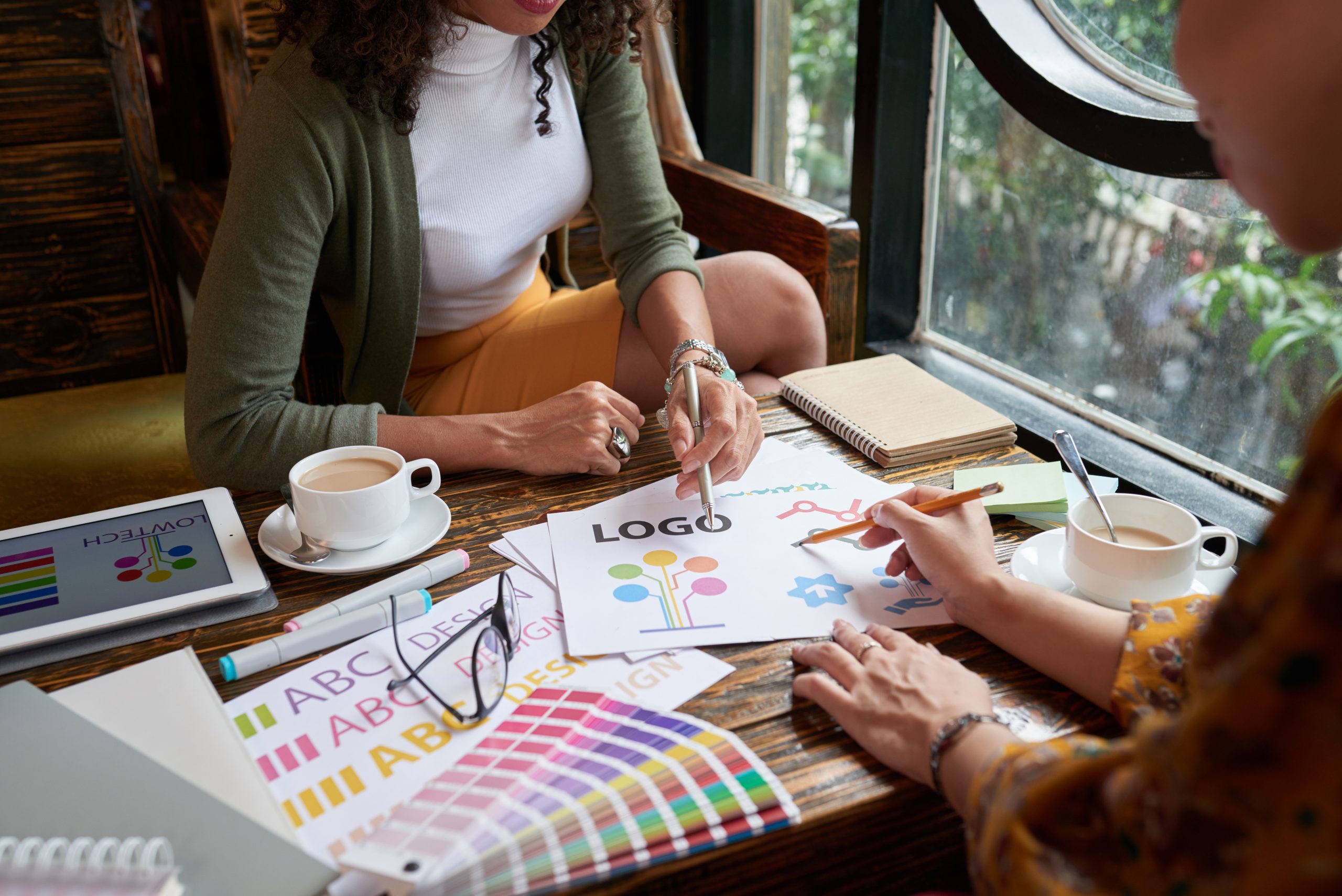 Zwei Designerinnen entwickeln gemeinsam ein Logo mit Farbmustern und Skizzen – Markenentwicklung durch AS Digital Consulting