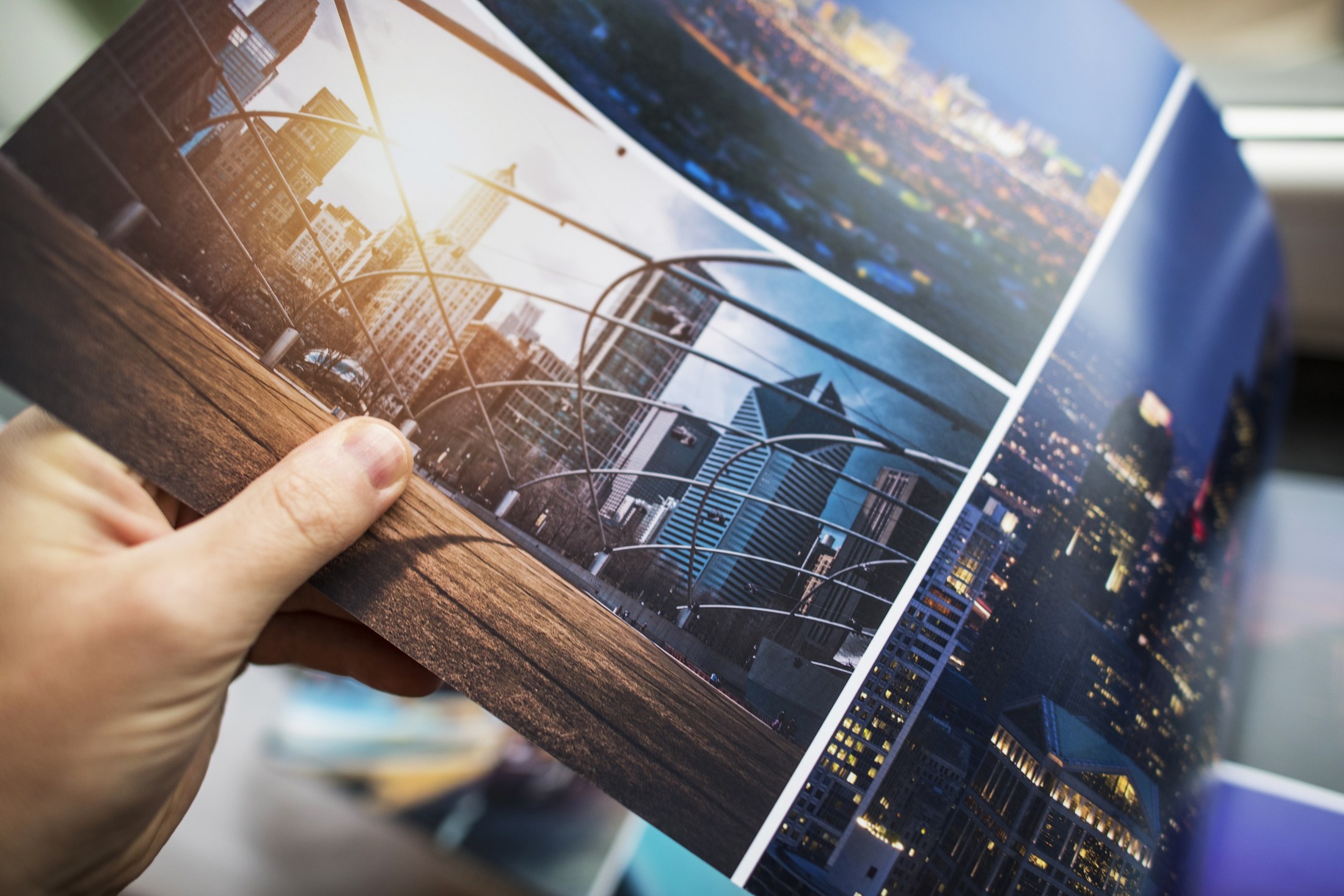 Hand hält gedruckte Fotoabzüge von Stadtansichten – Print- und Werbematerial im Corporate Design Ihrer Marke