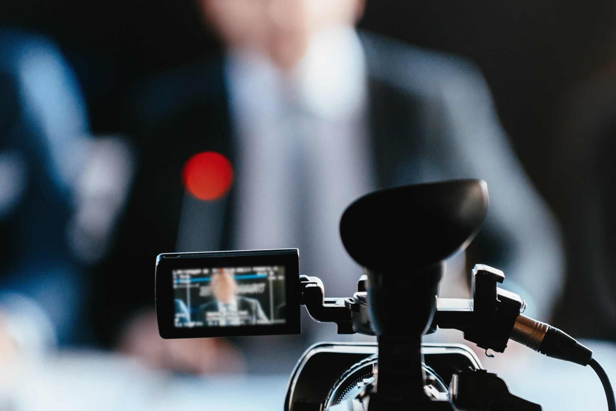 Videokamera mit ausgeklapptem Monitor vor einem unscharfen Sprecher – Idee und Planung vor dem Videodreh