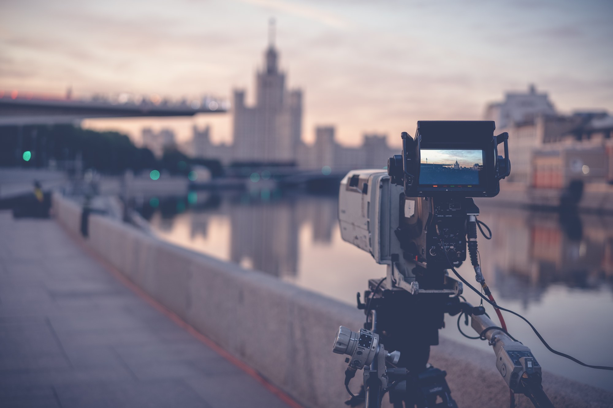 Videokamera auf einem Stativ am Flussufer bei Sonnenaufgang – Drehort und Drehplan